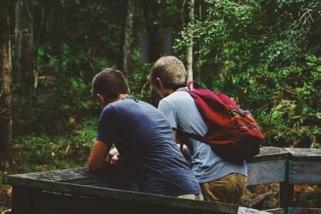 two men leaning on fence