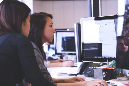 two women sitting in front of computer monitor